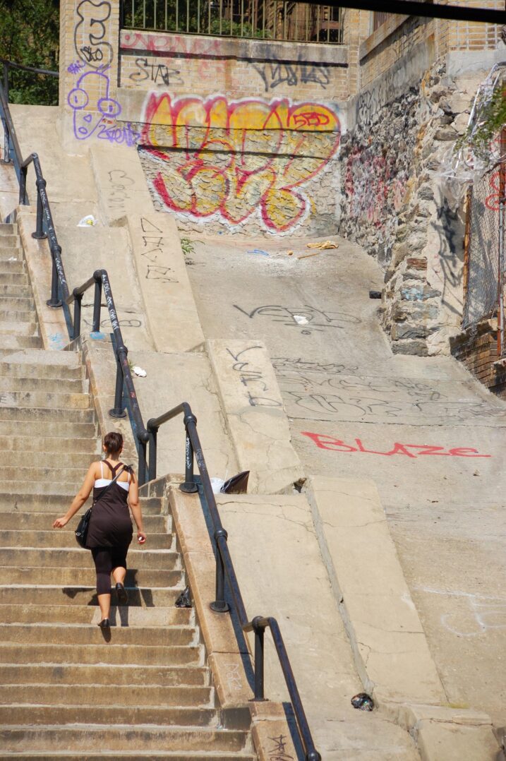 Person walking up graffiti-covered stairs
