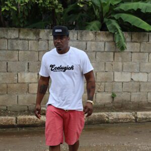 Man walking outdoors wearing a white T-shirt and pink shorts.