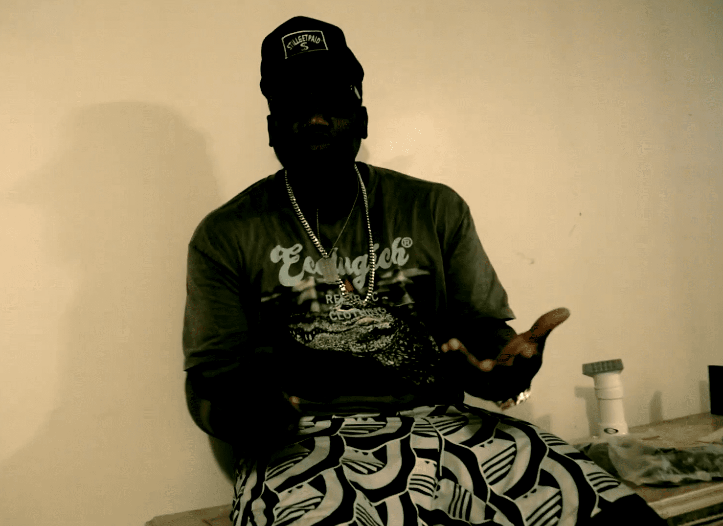 Person sitting against a plain wall with patterned pants and dark shirt. KUT SOTOR is an emerging artist whose sound is rooted in intensity, atmosphere, and identity. Blending cinematic elements with hard-edged rhythm and raw expression, his music feels less like a typical release and more like a statement. Each track carries a sense of tension and purpose, drawing listeners into a world that reflects discipline, pressure, and evolution. KUT SOTOR is not focused on chasing trends—instead, he builds from a foundation of control, presence, and originality, creating music that resonates beyond surface-level listening. Aligned with a larger vision, KUT SOTOR represents more than sound—he represents ownership. His work connects directly to a broader movement centered on mindset, structure, and self-defined success. With a growing catalog and a clear direction, he is positioning himself not just as an artist, but as a force tied to culture, brand, and long-term impact.